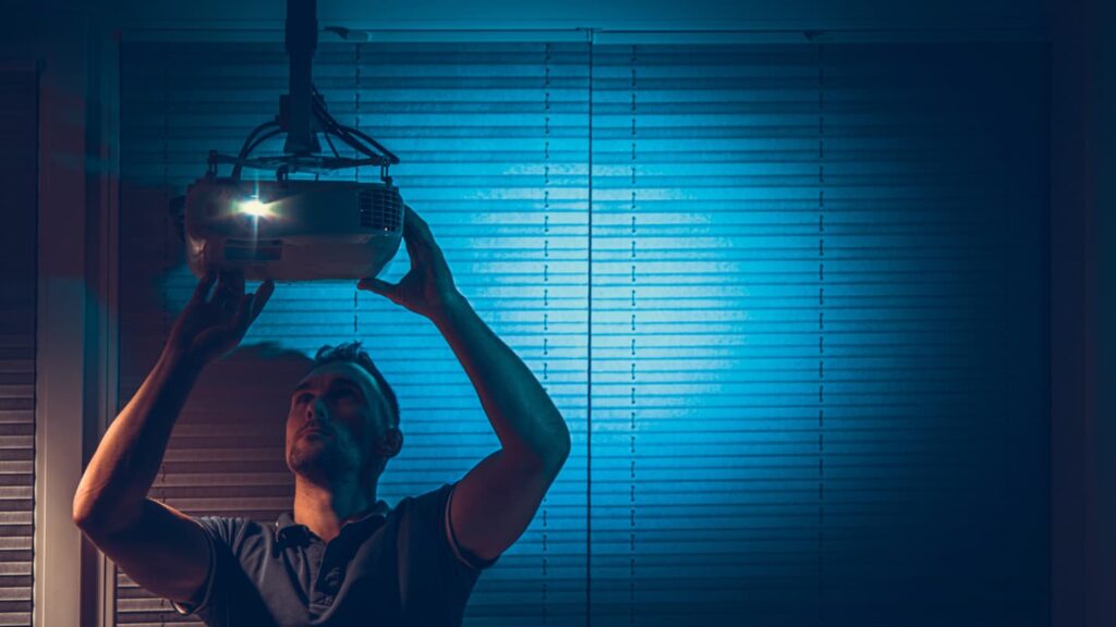 A Man Installs A Projector On The Ceiling Of A Room