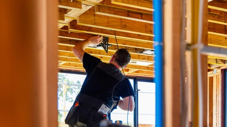 An AV company technician measures for precision while installing.