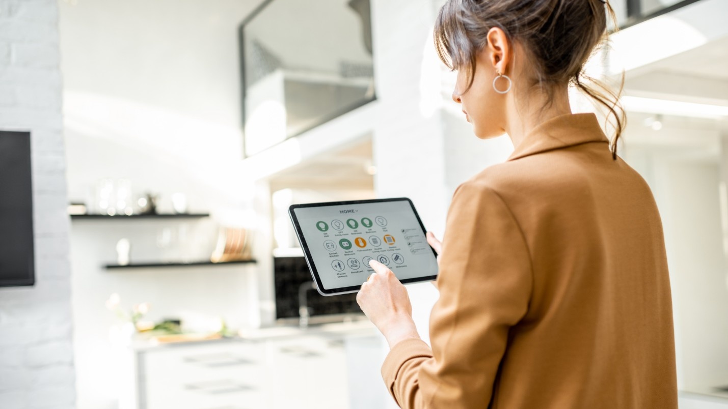 A woman using a smart device to connect with her smart home.