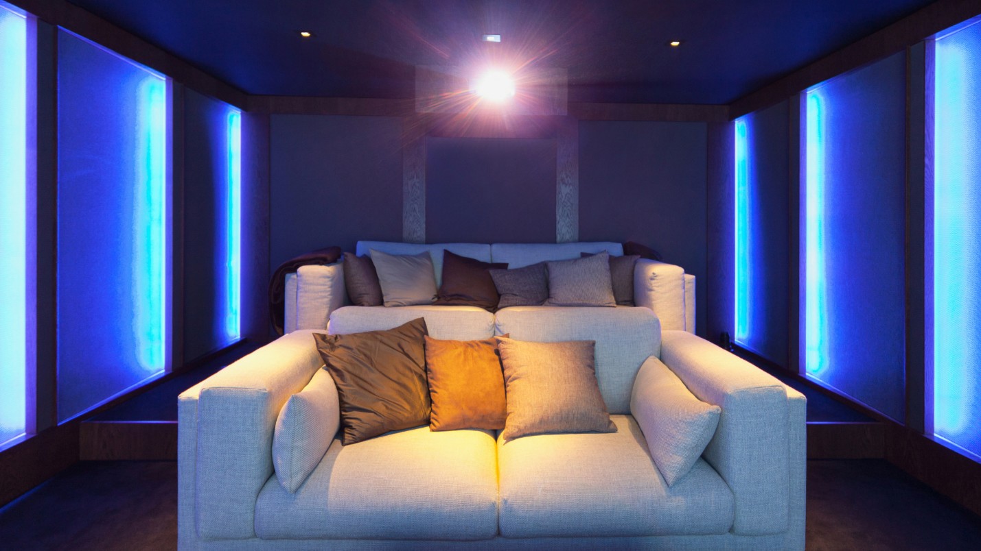 Couches and a ceiling-mounted projector in a home theater.