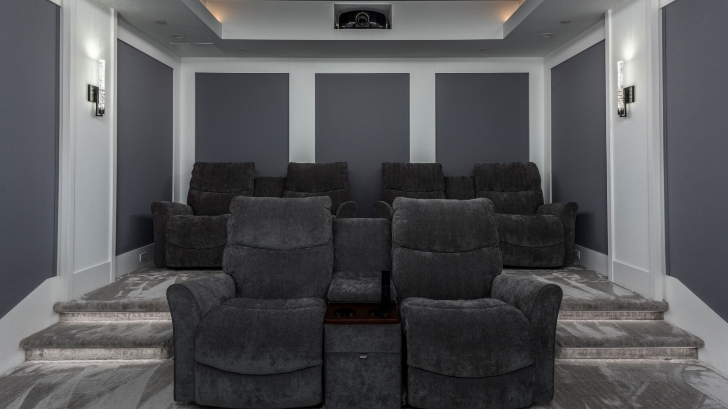 A modern home theater with four sets of luxury furniture.