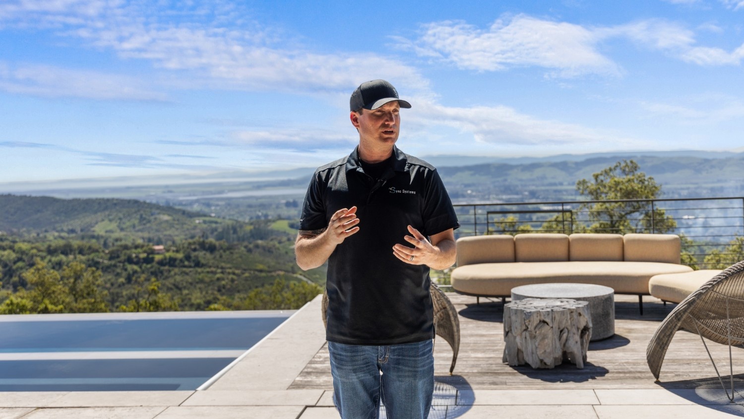 An AV technician stands in the back patio of a luxury home.