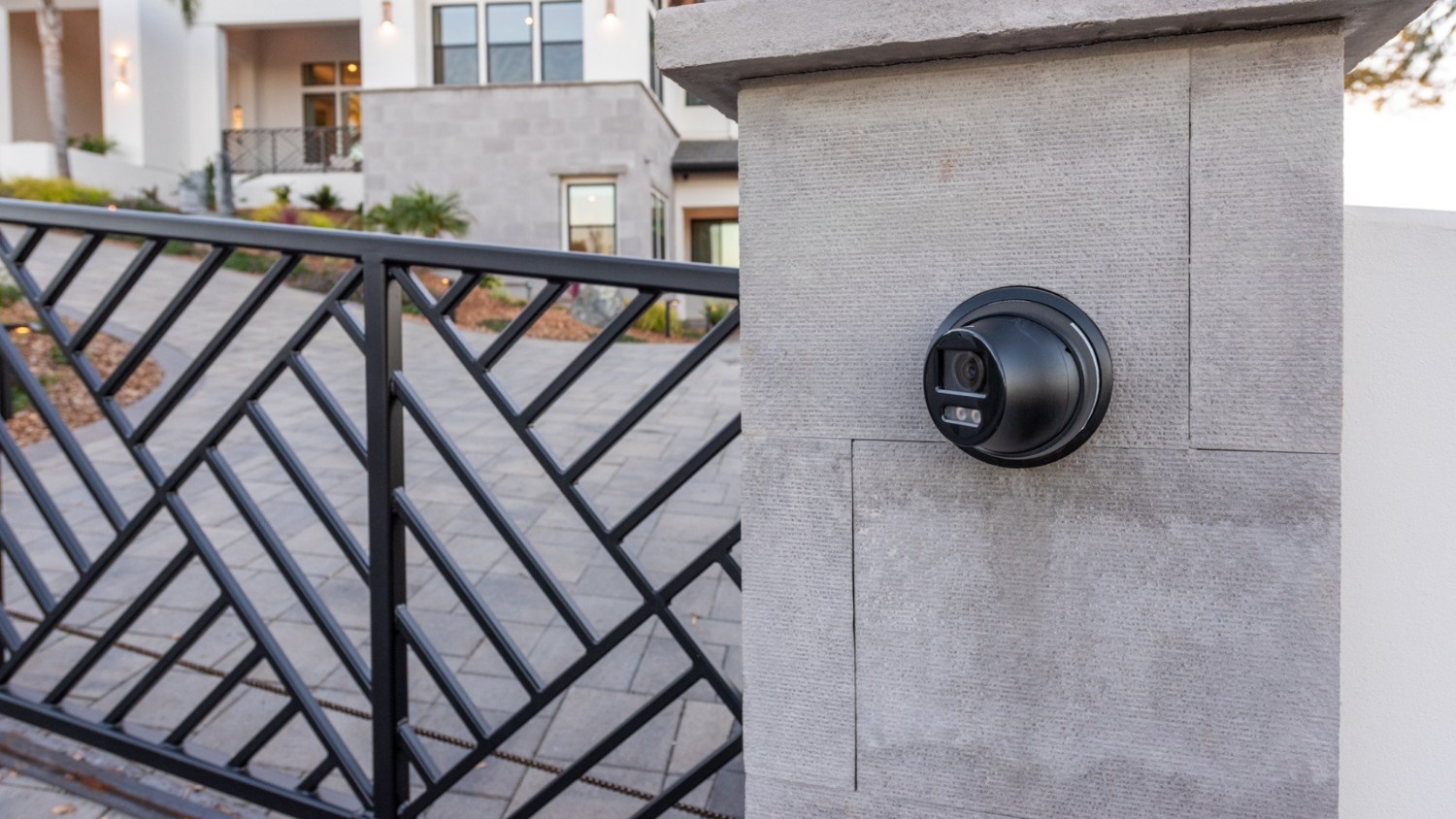 The gate to a luxurious home with a surveillance camera installed out front.