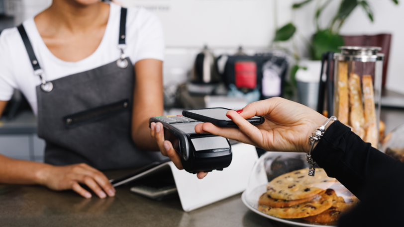 A customer at a commercial business uses their phone to pay for a transaction.