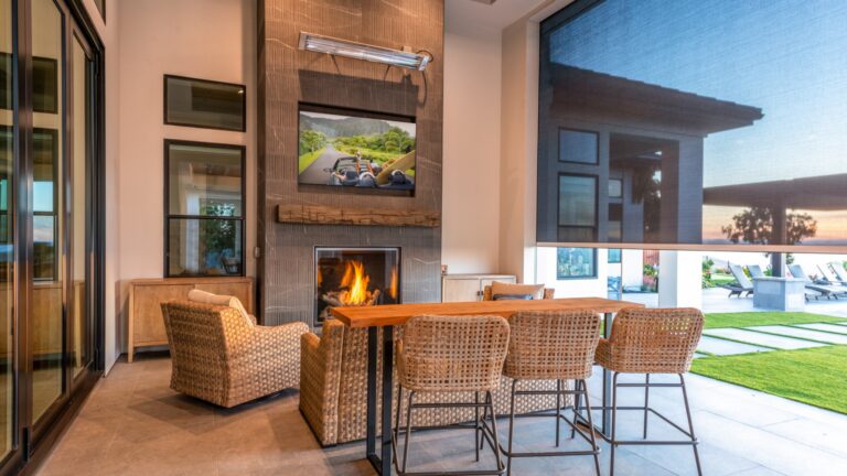 A luxury outdoor dining area with home automation elements like motorized shades.