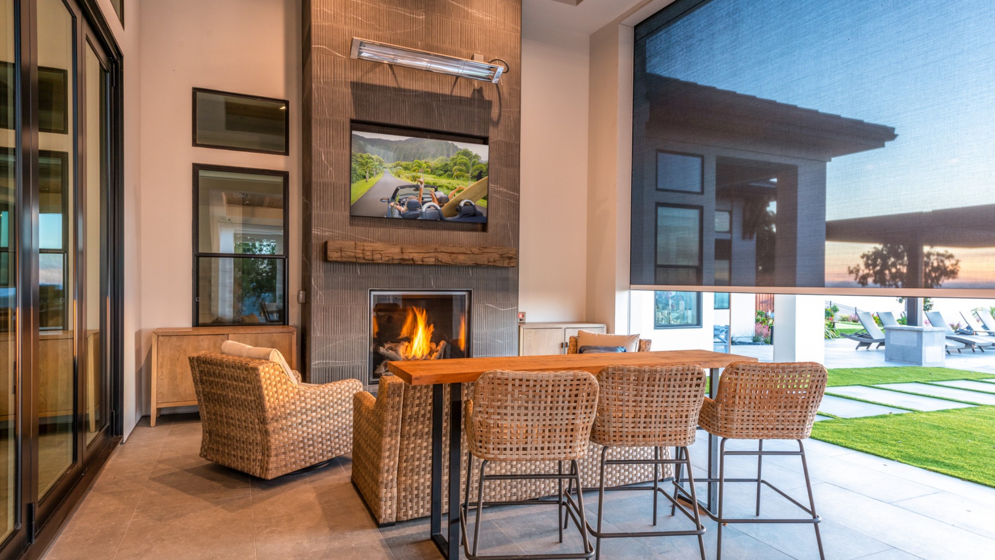 A luxury outdoor dining area with home automation elements like motorized shades.