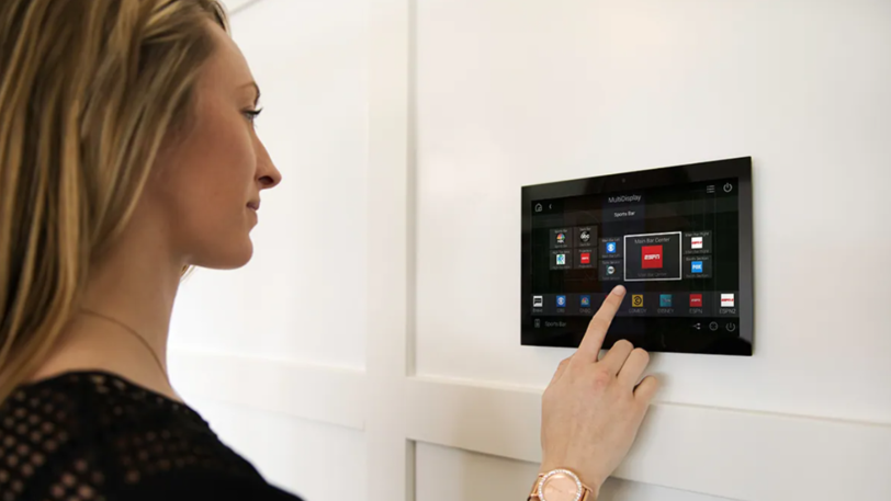 A woman uses the control panel installed on the wall of her smart home.