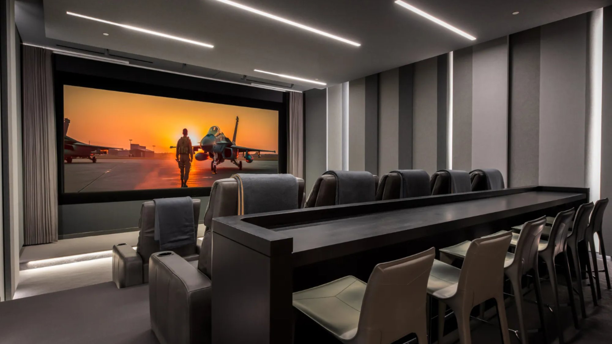 A large home theater with rows of comfortable seating and embedded ceiling lights.