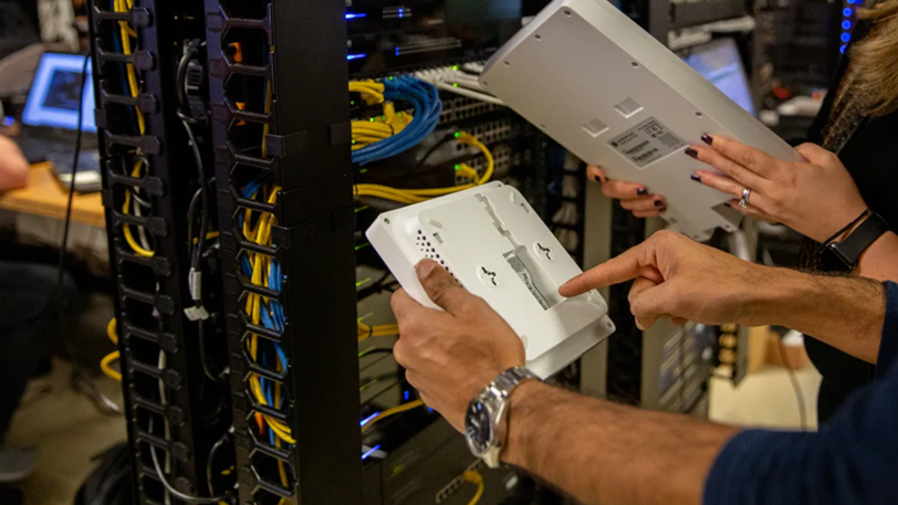 An internet networking tower behind a man pointing to a plastic compartment.